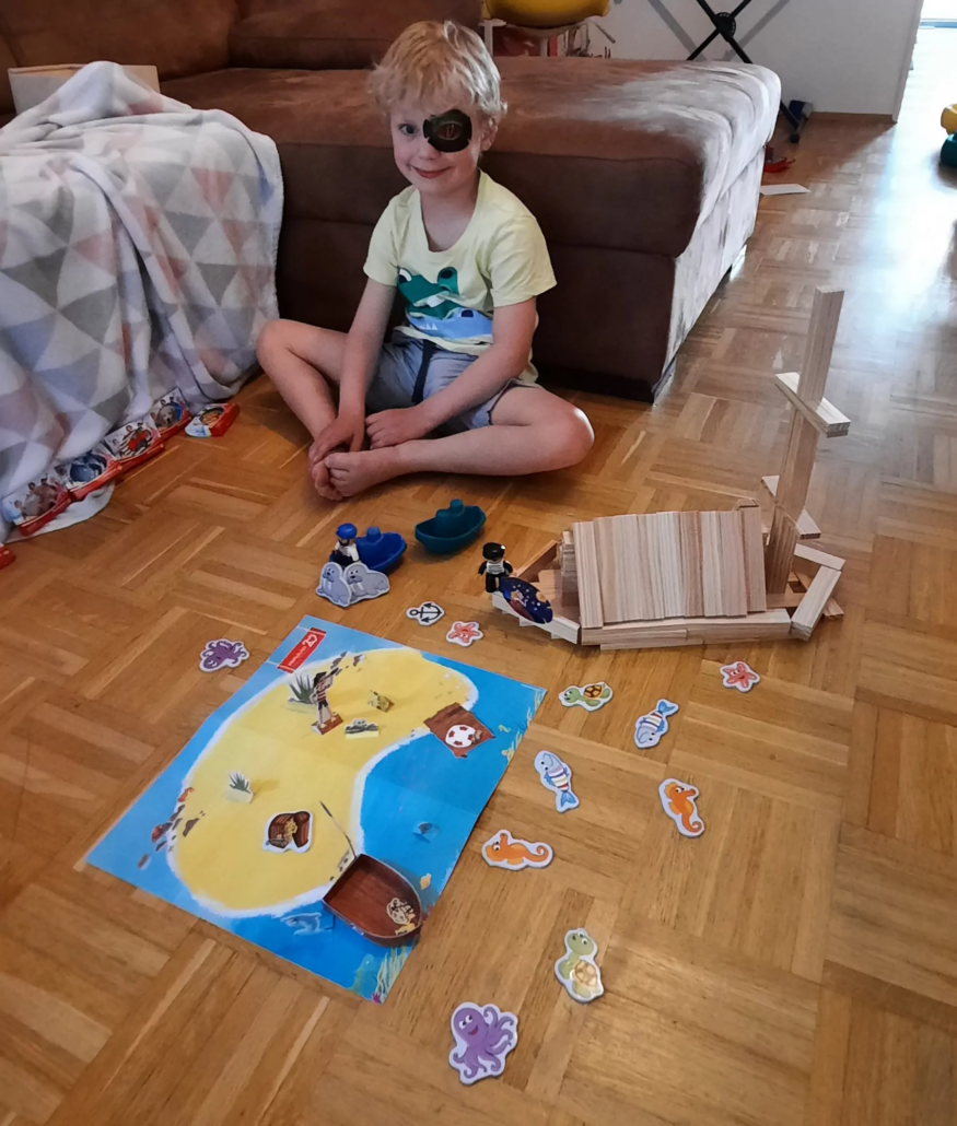 Junge mit Augenpflaster spielt mit Pirateninsel-Bastelbogen