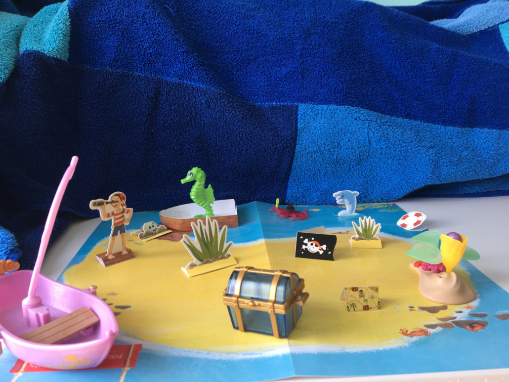 Piratoplast Bastelbogen Pirateninsel aus Pappe ergänzt um Spielzeuge wie Schiff, Seepferdchen und Schatztruhe