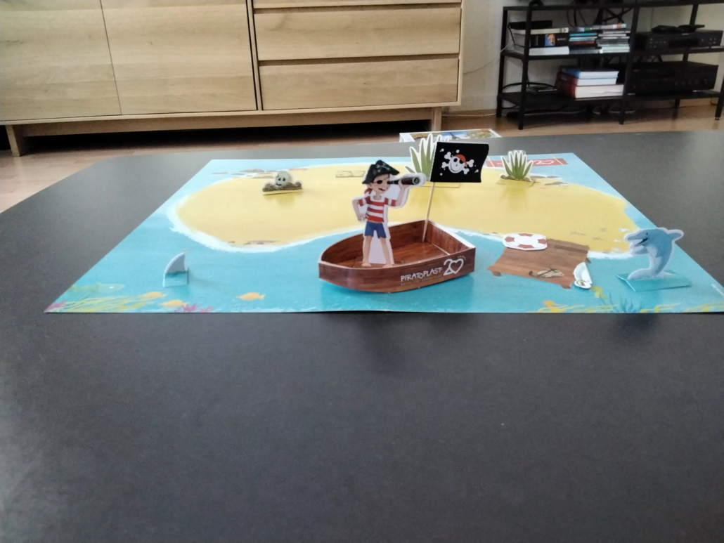 Nahaufnahme von Bastelbogen: Pirateninsel, Piratenschiff mit Piratoplast-Flagge, Piratenjungen und Delfin