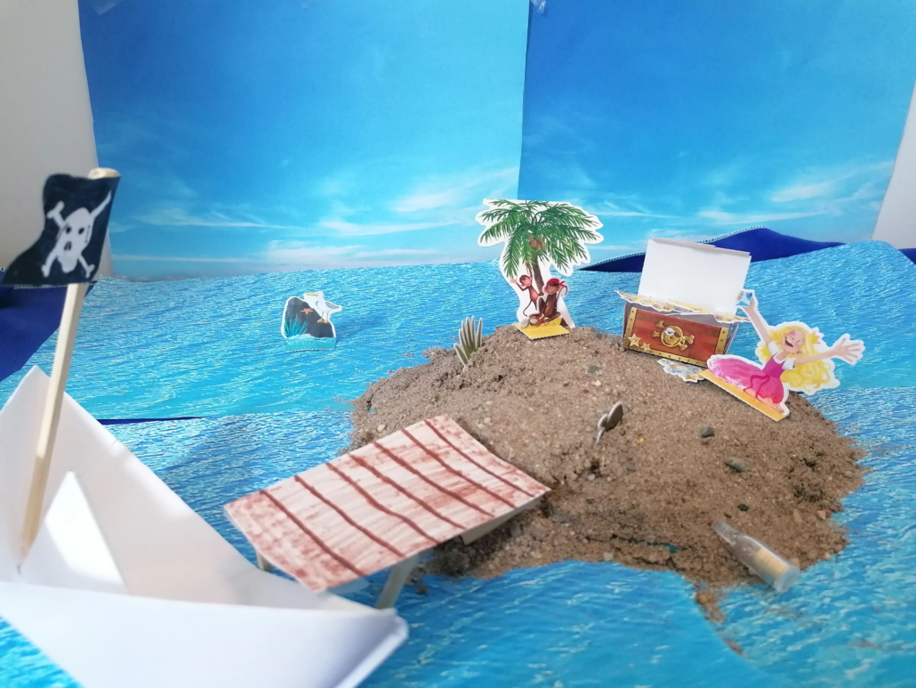 Pirateninsel aus Sand mit einem Steg hin zu einem Papierboot