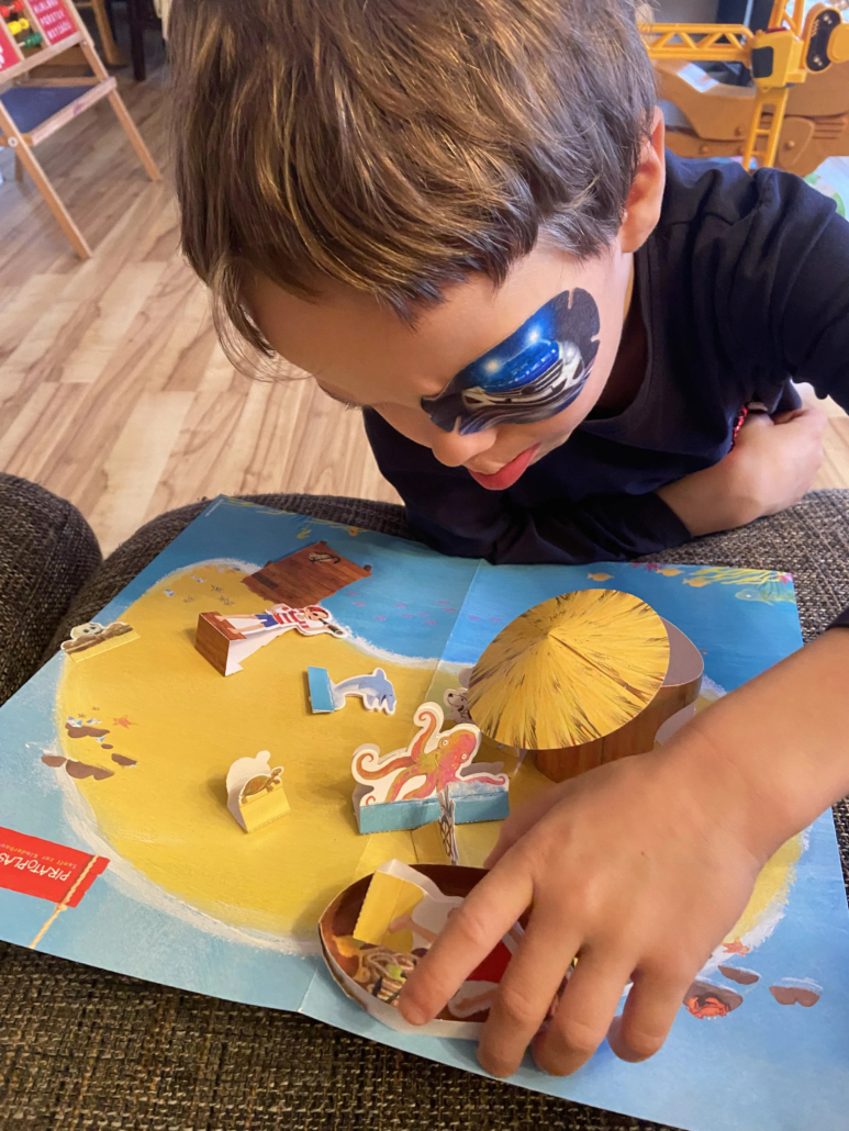 Kind mit Augenpflaster spielt mit Elementen des Piratoplast-Bastelbogen