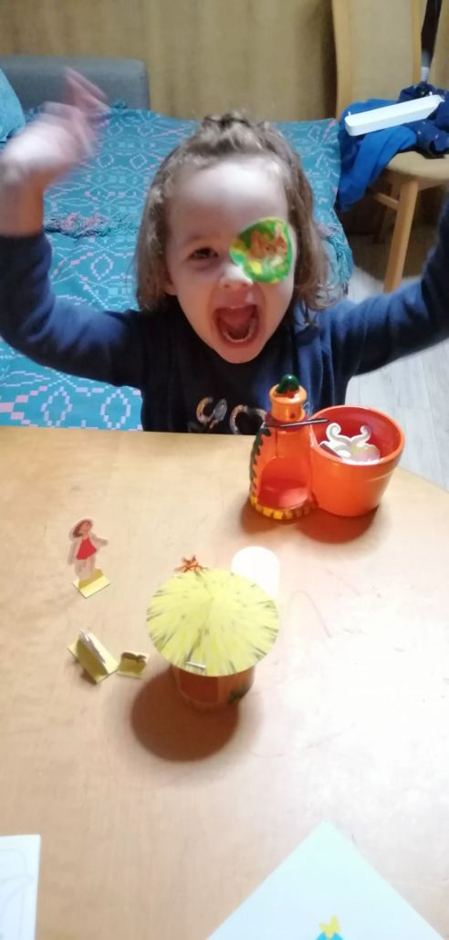 Kind mit Augenpflaster freut sich mit den Elementen des Bastelbogens von Piratoplast zu spielen