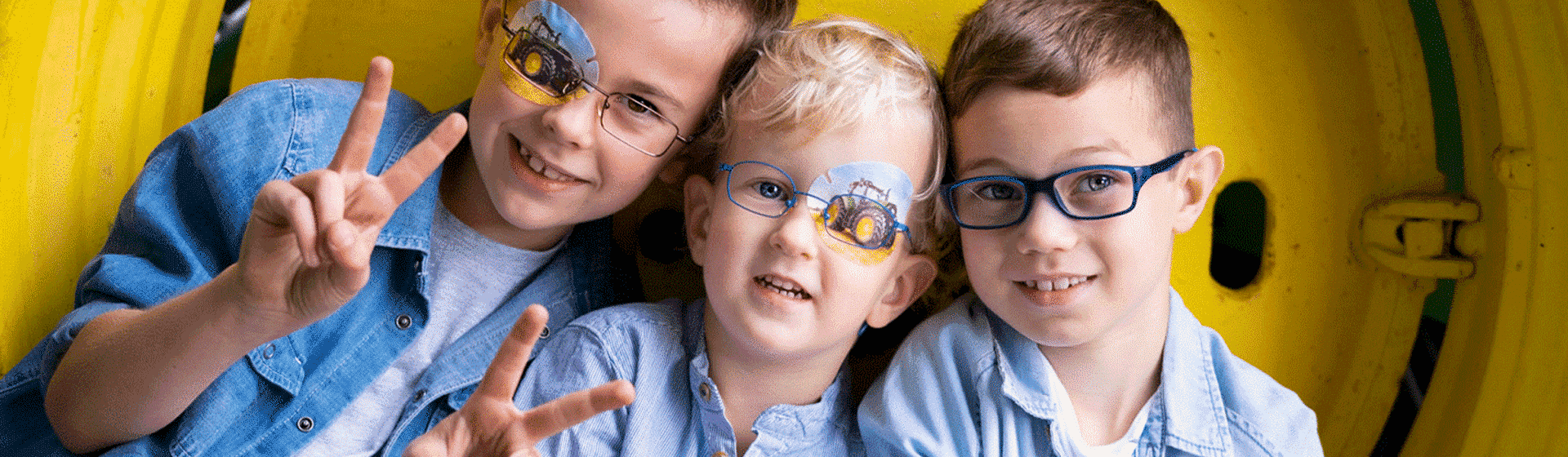 Drei Kinder tragen Brille und Trecker Aufgenpflaster
