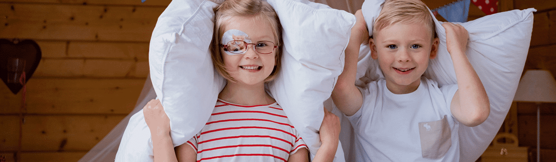 Kinder mit Augenpflaster spielen mit Kissen